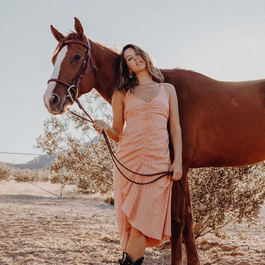 A woman wearing cowboy boots standing with a horse