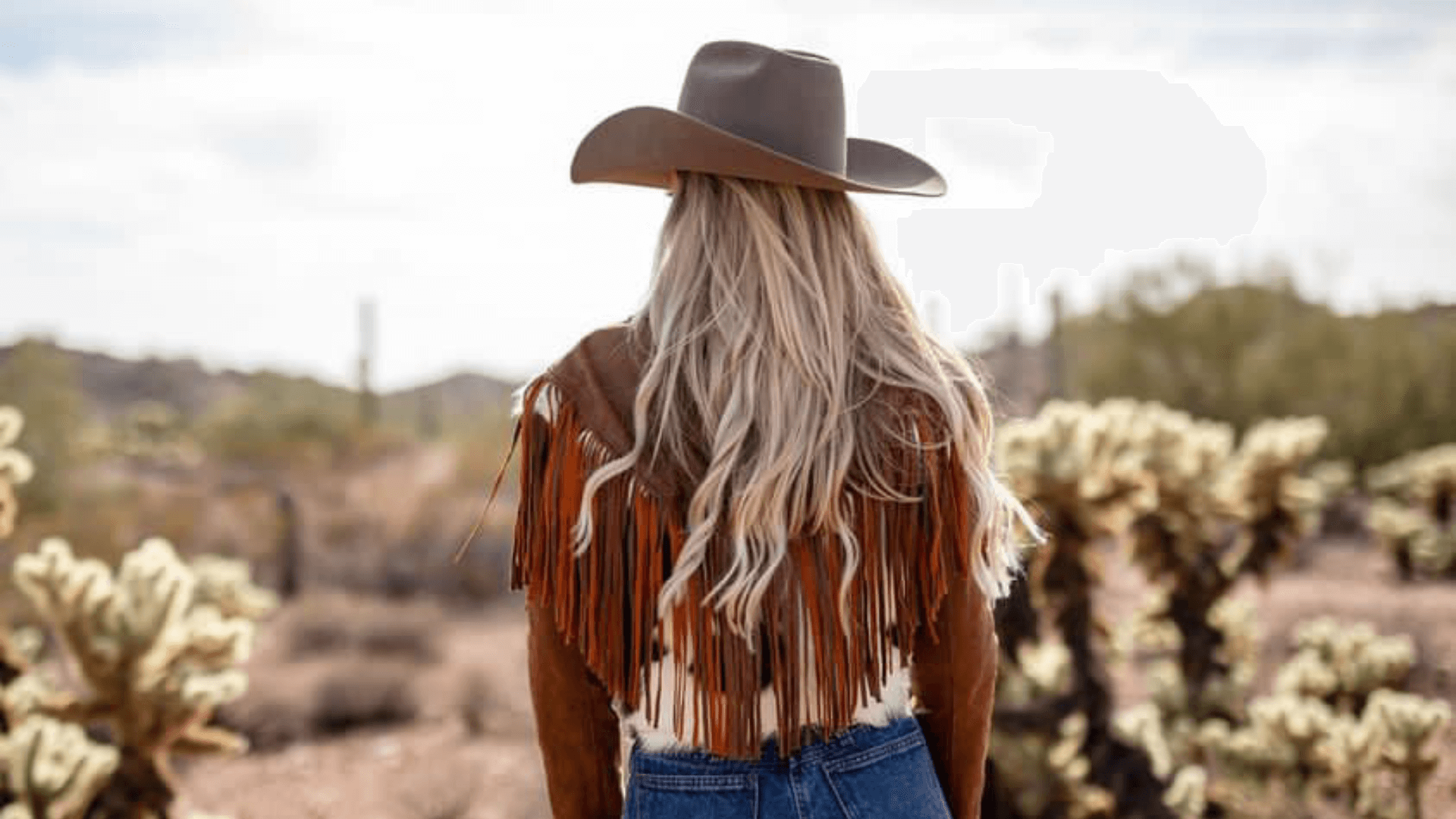 Woman wearing the Charlotte suede & leather cowhide fringe jacket wearing a western hat