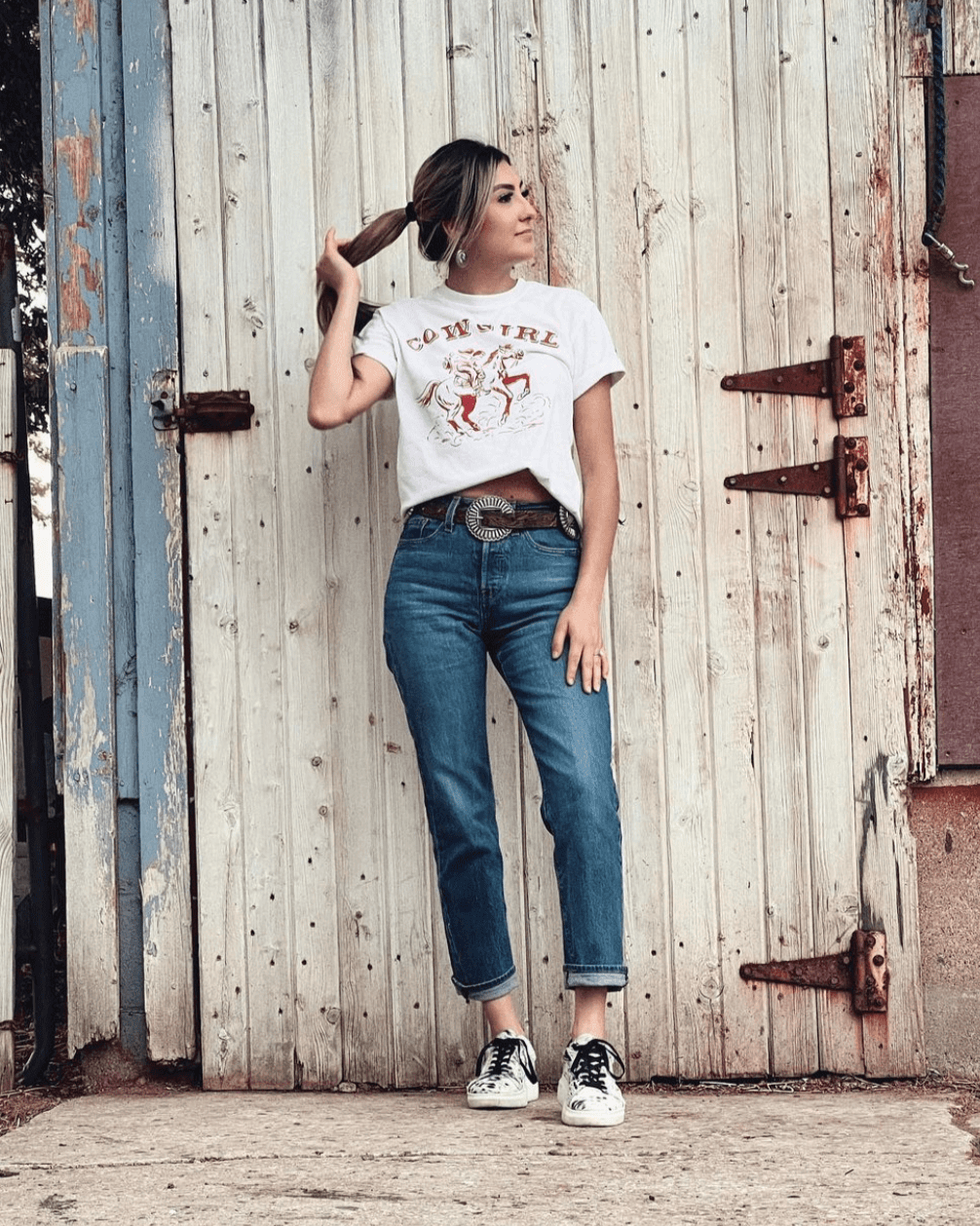 Woman wearing Stiefeld Julia hair-on-hide sneakers standing on a rustic wooden boardwalk